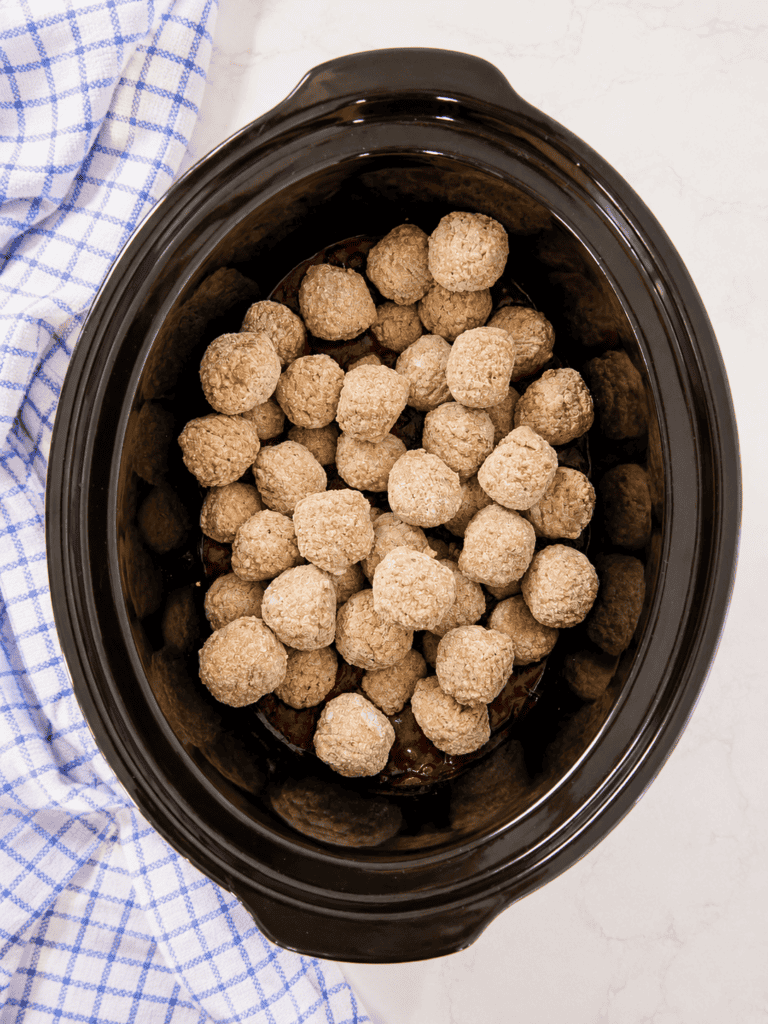 Frozen meatballs added to grape jelly and BBQ sauce in a slow cooker before cooking. This crockpot grape jelly meatballs recipe is an easy appetizer for parties, holidays, and game day.