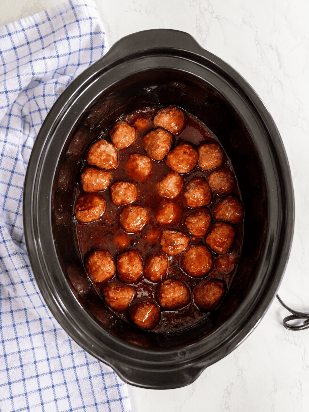 Slow cooker grape jelly meatballs simmering in a rich barbecue and grape jelly sauce until hot and coated. An easy crockpot meatballs recipe made with frozen meatballs and simple ingredients.