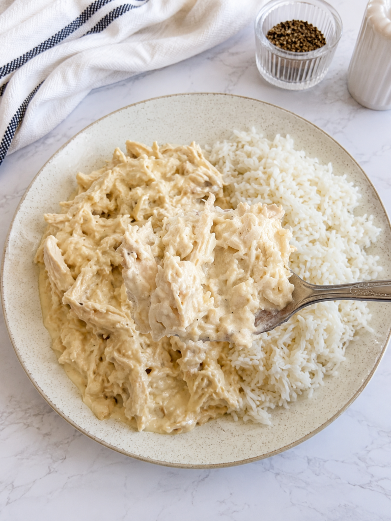 Close-up spoonful of creamy bacon ranch chicken with tender shredded chicken and rich ranch sauce served over white rice.