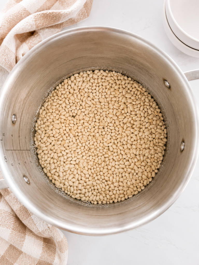 Dry navy beans soaking in water before cooking, the first step for making homemade slow cooker baked beans from scratch.