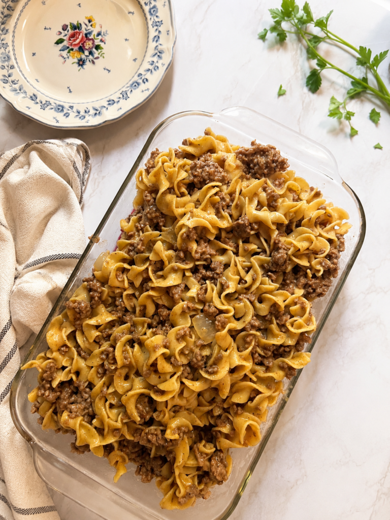 Classic beef stroganoff recipe made with ground beef, egg noodles, mushrooms, onions, and a creamy sour cream sauce served in a glass baking dish. This easy homemade beef stroganoff is a comforting family dinner made with beef broth and Worcestershire sauce, perfect for busy weeknights and traditional comfort food lovers.