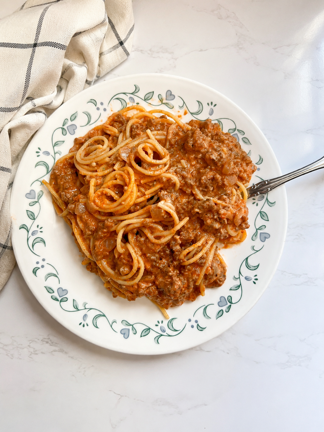 Creamy cheesy ground beef spaghetti served on a white dinner plate with a rich tomato cream sauce, seasoned ground beef, and tender spaghetti noodles for an easy family dinner recipe.