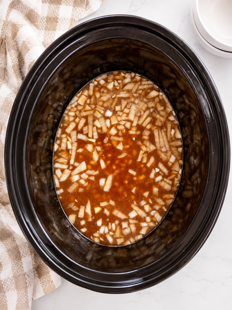 Soaked navy beans and diced onion added to the slow cooker with homemade baked bean sauce before adding the meat.