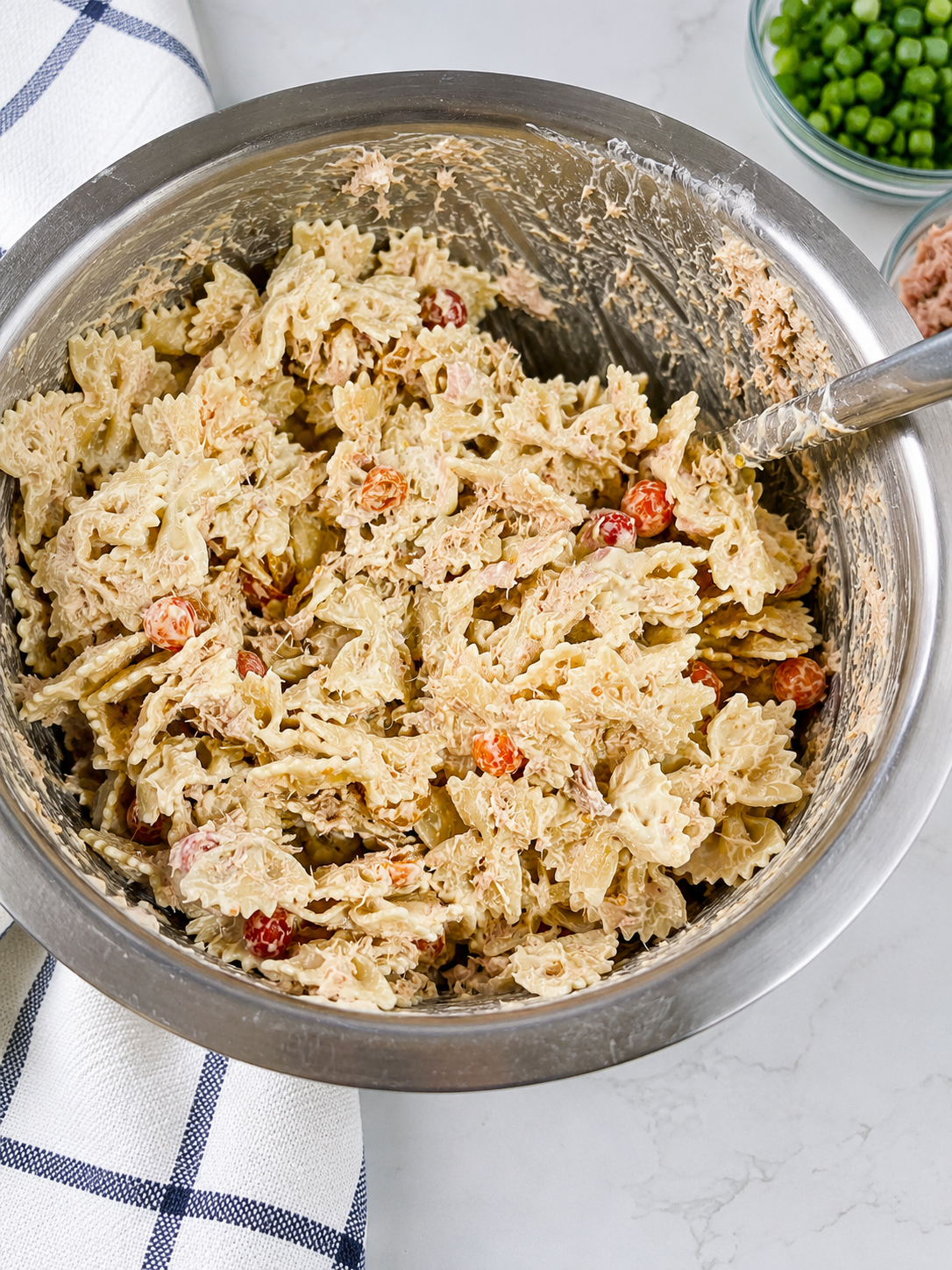 Easy homemade tuna pasta salad recipe made with farfalle pasta, tuna, cherry tomatoes, mayonnaise, and diced onions in a large mixing bowl, perfect for summer picnics, potlucks, and family dinners.
