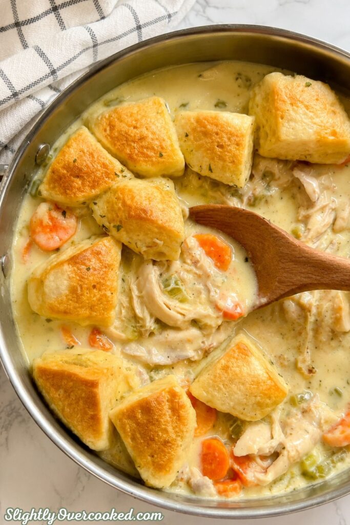 Creamy chicken and dumplings with tender chicken, vegetables, and golden biscuit dumplings in a skillet