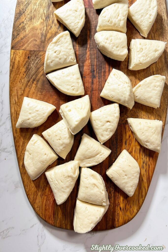 Unbaked biscuit dumplings cut into small pieces and arranged on a wooden cutting board