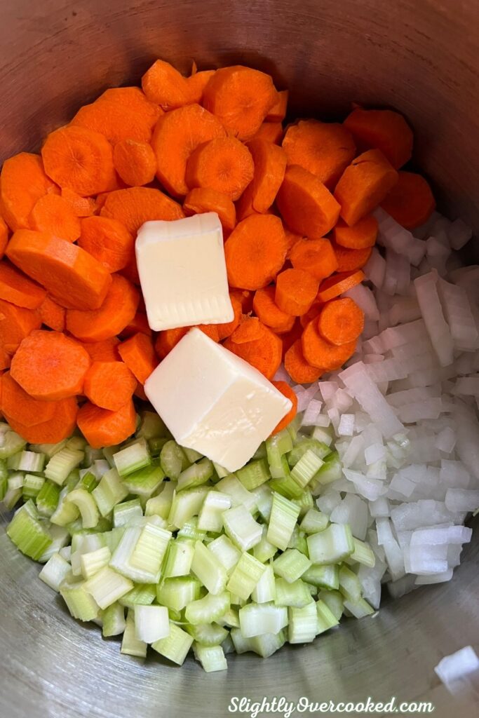 Sliced carrots, diced celery, chopped onion, and butter prepared for homemade chicken and dumplings