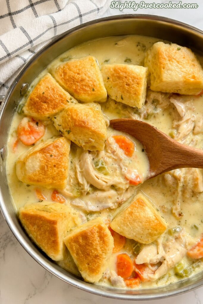 Creamy chicken and dumplings with tender chicken, vegetables, and golden biscuit dumplings in a skillet