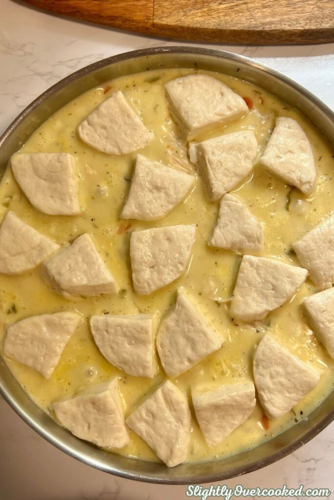 Raw biscuit dumplings arranged over creamy chicken filling.