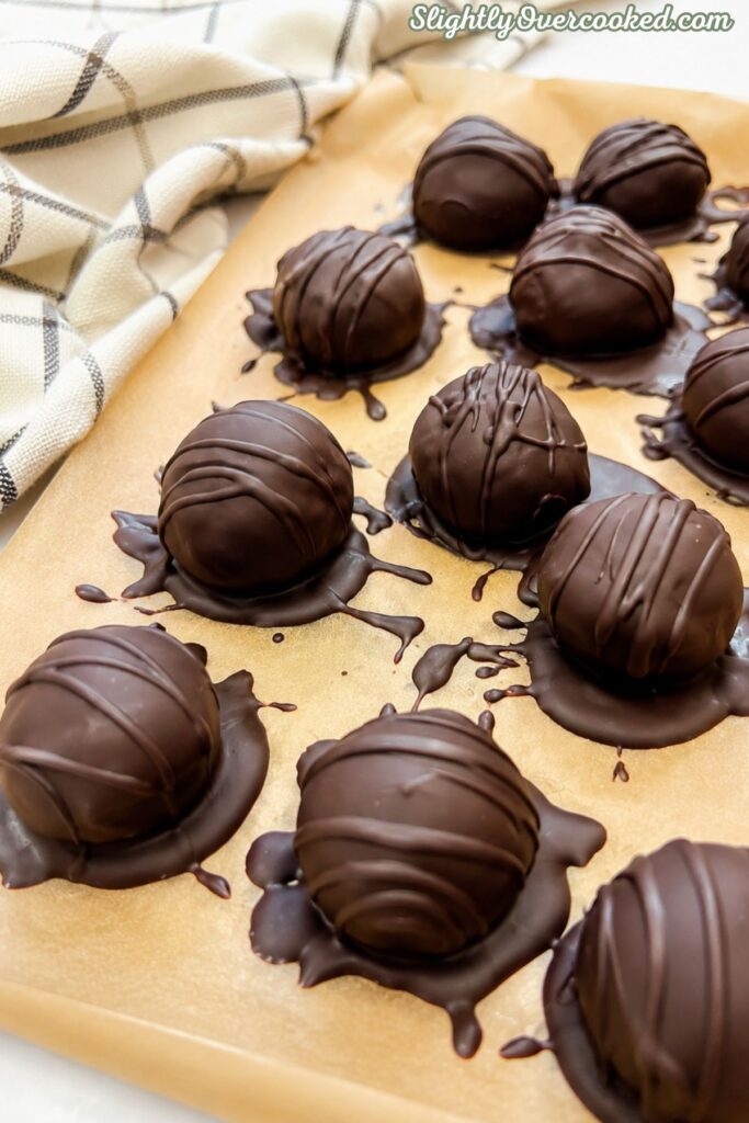 Homemade chocolate-covered Oreo truffle balls on a parchment-lined baking sheet