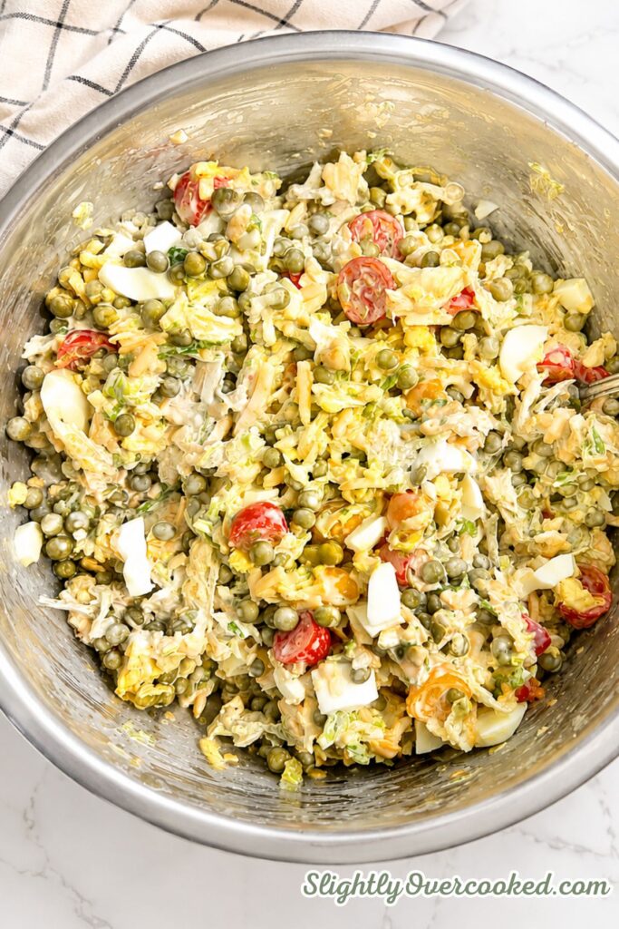 Creamy pea salad mixed together with lettuce, peas, cheddar cheese, bacon, tomatoes, and hard-boiled eggs