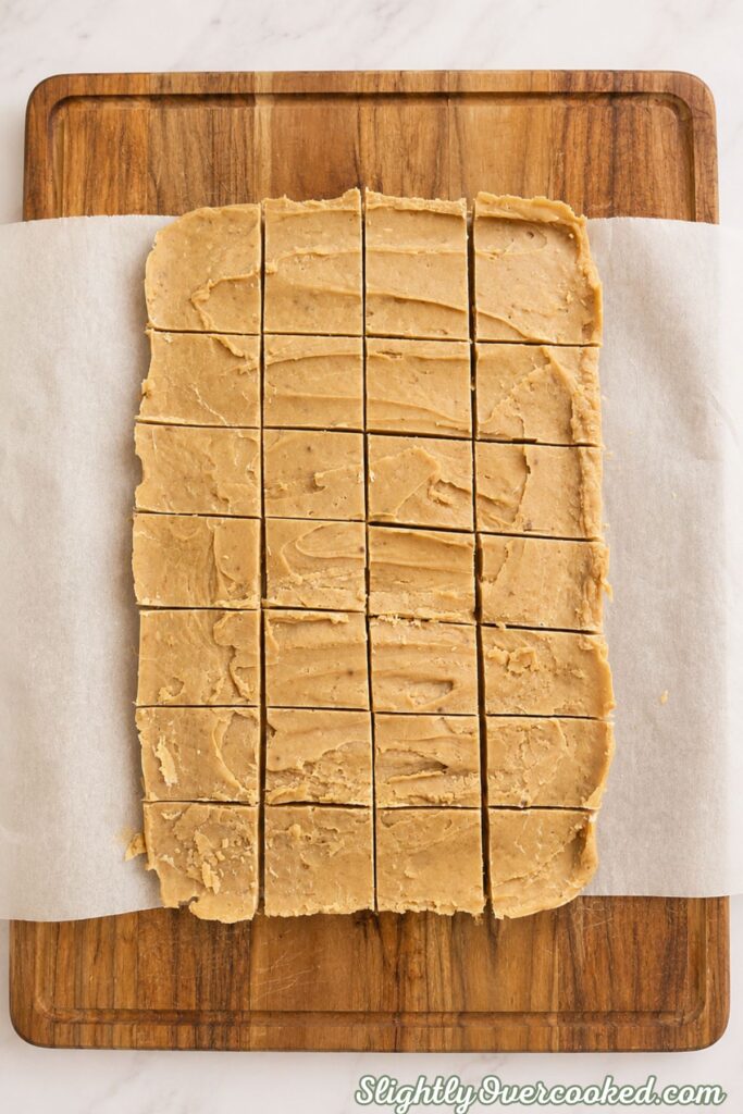 Homemade peanut butter candy cut into small squares on a wooden cutting board