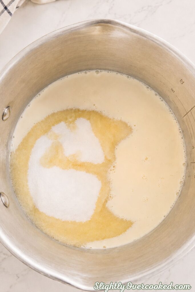 Granulated sugar and evaporated milk combined in a saucepan before cooking