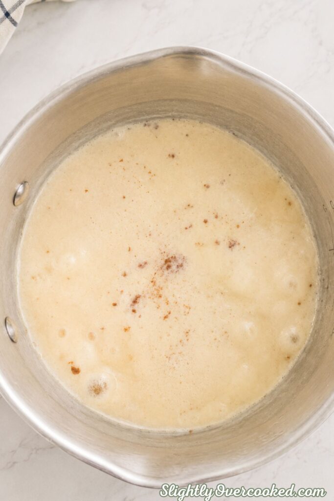 Sugar and evaporated milk heating together in a saucepan to make homemade candy